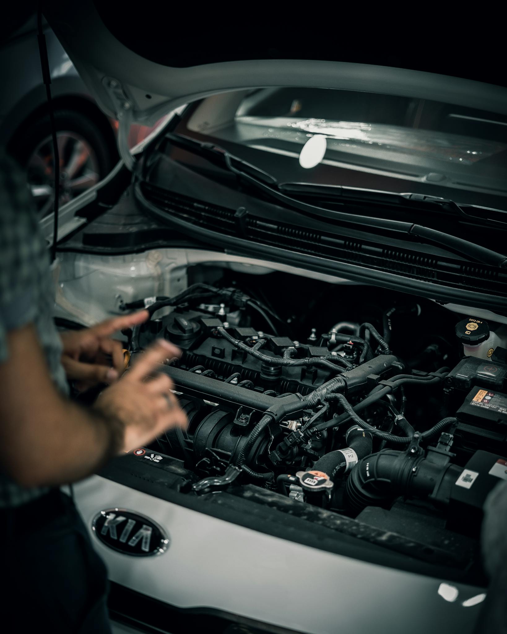 Mechanic inspecting a car engine for maintenance work in a garage.